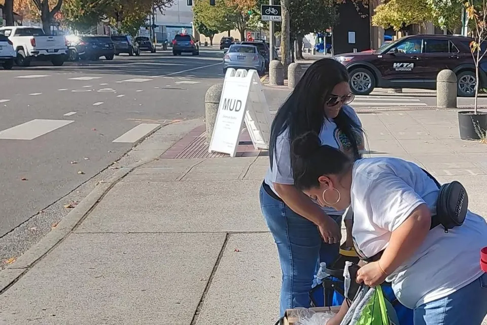 Two volunteers in A Better Way Out shirts preparing supply bags